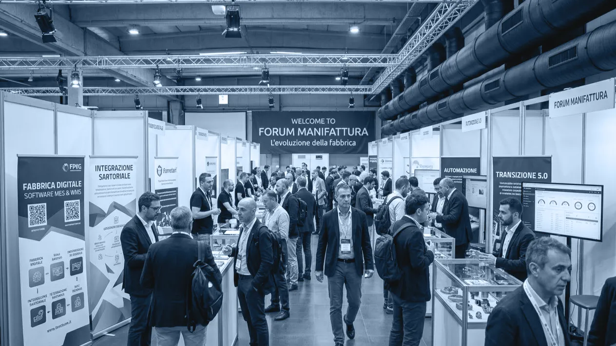 Visitatori tra gli stand del Forum Manifattura 2025, sotto lo striscione di benvenuto dell'evento